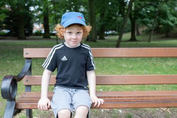 A young boy at a community event, sitting on a bench