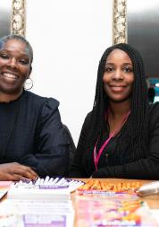 two female staff members sitting behind a desk full of stationary